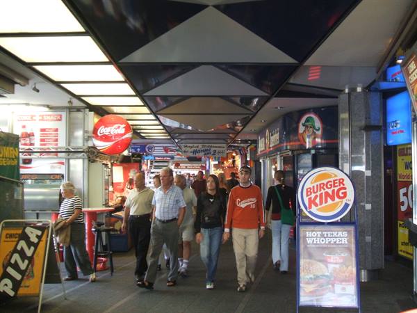 People walk through a covered shopping arcade with Burger King and Coca-Cola signs