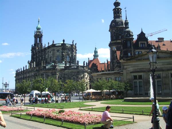 Dresden Hofkirche: tourists among flowerbeds and fountain under blue sky