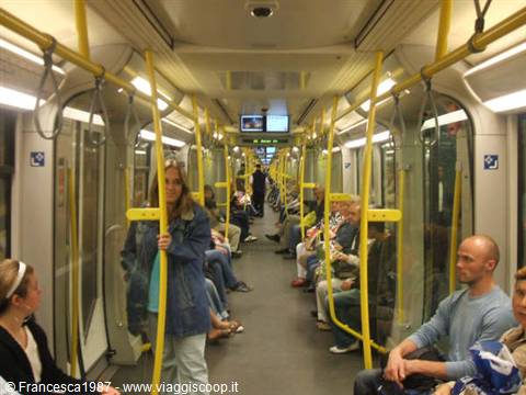 Subway car interior with seated passengers and yellow grab poles