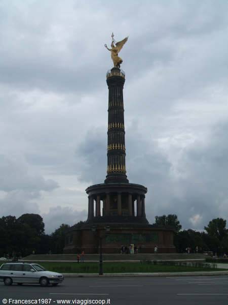 Berlin Victory Column with golden angel statue under cloudy sky, cars passing by