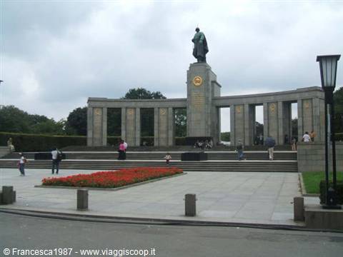 Soviet Memorial in Tiergarten: stone statue, red flowers, tourists