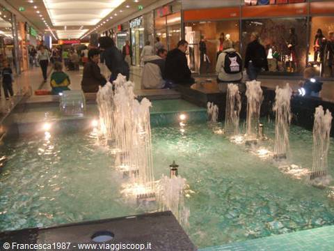 Illuminated fountains inside a shopping mall, people seated nearby