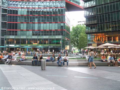 People resting on steps at Potsdamer Platz among glass buildings