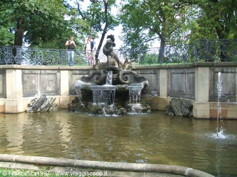 Baroque stone fountain with triton statue, cascades and water jets in a park