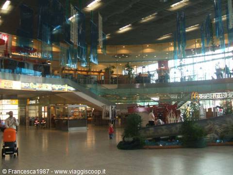 Shopping mall interior with escalators, blue flags and McDonald's sign