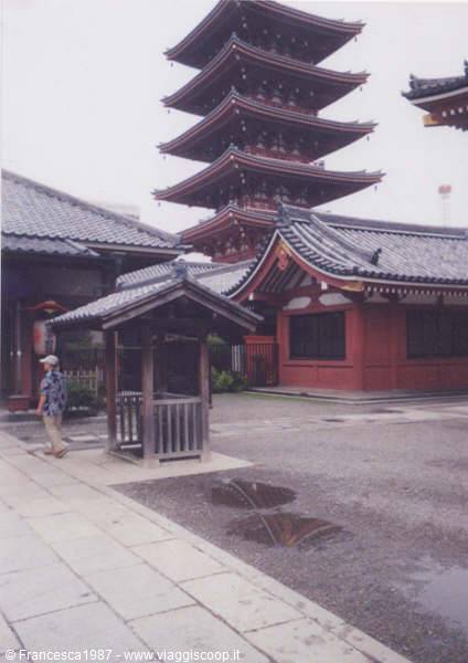 Five-story pagoda of Senso-ji temple, man walks under gray sky