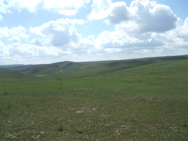 Dark green grassy hills under a sky full of white clouds