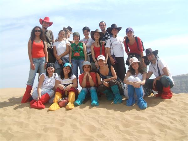 Group of tourists in colorful sand boots and hats posing on a dune