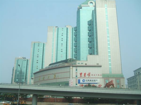 Green glass skyscraper above a highway overpass, Chinese signs, hazy sky