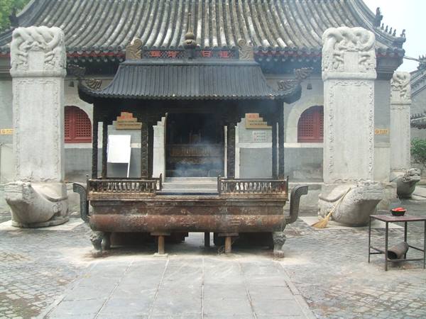 Smoking bronze incense burner at Baiyun Temple, between stone steles on turtle bases
