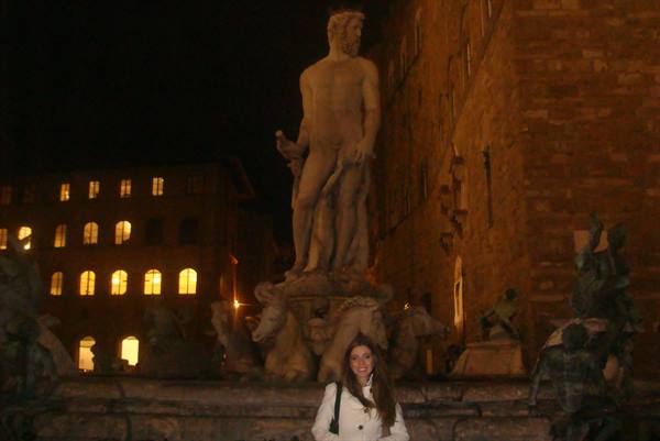 Woman in white coat in front of the Neptune fountain in Florence, at night