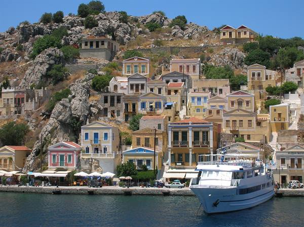 White ferry docked at Symi harbor, colorful houses on the rocky hill
