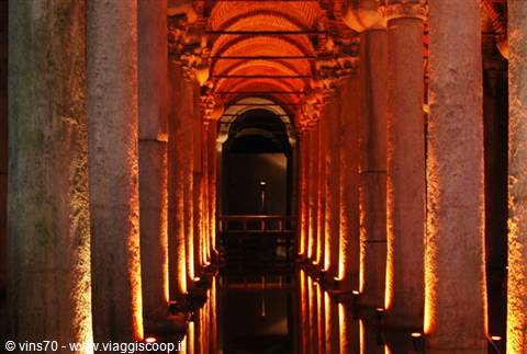 Marble columns inside Istanbul's Basilica Cistern, amber light reflecting on water