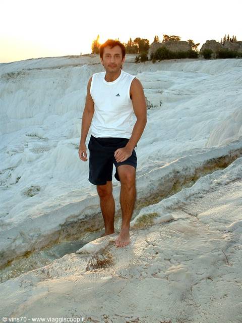 Barefoot man on white Pamukkale travertine terraces in golden light
