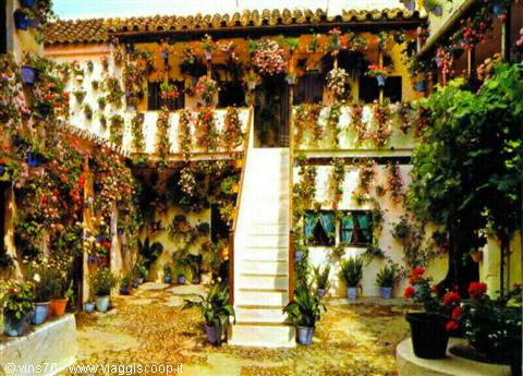 Andalusian courtyard with white staircase, flower-covered walls and terracotta pots