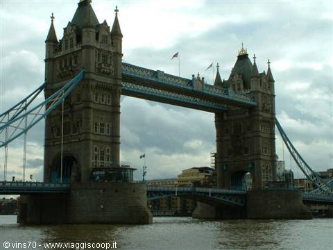 Tower Bridge in London, stone towers over the Thames under cloudy sky