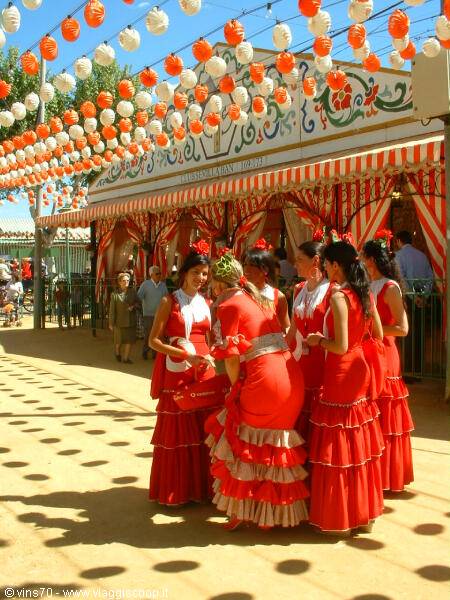 Women in red flamenco dresses under paper lanterns at Seville's Feria de Abril