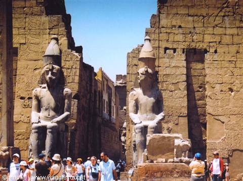 Seated statues of Ramses II at Luxor Temple, tourists among stone colossi