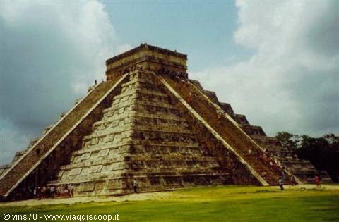 Kukulcán pyramid at Chichén Itzá, tourists climbing stairs under cloudy sky