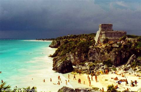 Tourists on the beach below the Mayan ruins of Tulum by turquoise sea
