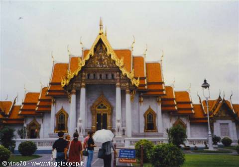 Tourists with umbrella in front of Wat Benchamabophit white marble temple