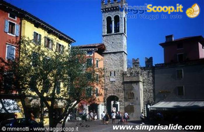 Stone Apponale Tower in Riva del Garda, tourists in the square under blue sky