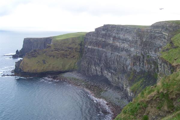 Cliffs of Moher: layered rock walls over the ocean, green grass, overcast sky