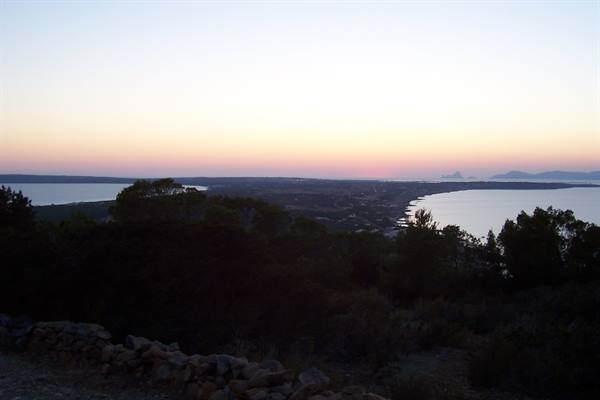 Stone wall and Mediterranean shrubs above Alghero bay at dusk