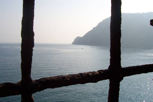 sea and cliff seen through a rusty iron grate