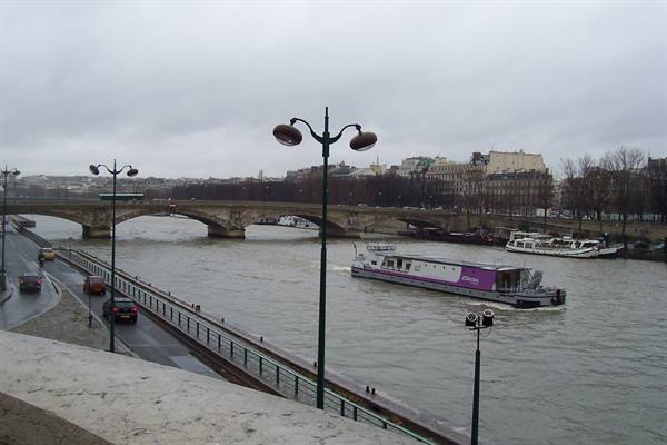 Purple barge on the Seine, stone bridge, wet quay under grey sky