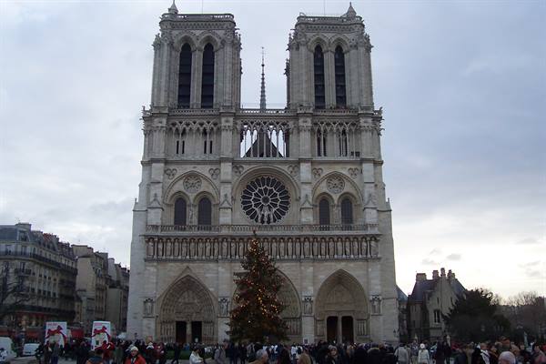 Gothic facade of Notre-Dame in Paris with Christmas tree and tourists
