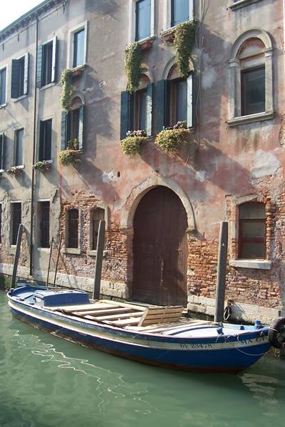 Blue boat moored along a canal in front of old Venetian houses