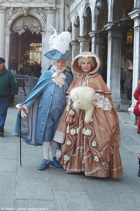 Couple in eighteenth-century costumes with feathers and capes in St Mark's Square, Venice
