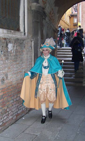 Carnival costume with turquoise cape near a bridge in Venice