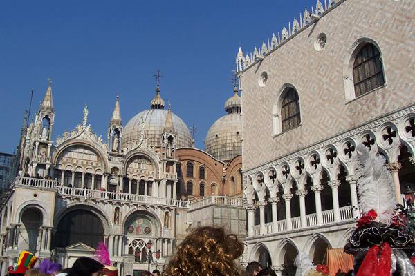 Venetian carnival masks with feathers before Doge's Palace and St Mark's Basilica