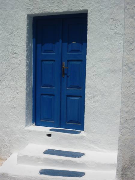 Blue wooden door on whitewashed wall, plastered steps