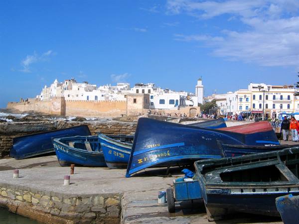 Blue overturned fishing boats on stone pier before Essaouira ramparts