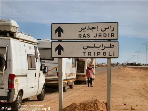 Road sign to Ras Jedir and Tripoli, campervans parked on sand