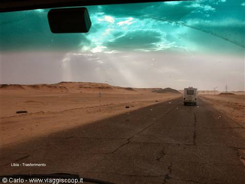 Through the windshield, truck on asphalt desert road in Libya, dusty sky