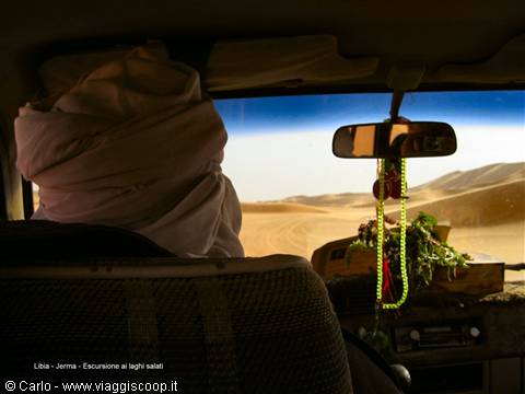 Driver in white turban steers the 4x4 across sand dunes