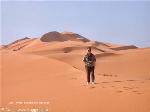 Woman standing on sand among sandstone dunes, Libya