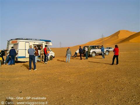 Travelers around camper van and SUV among sand dunes, Ghat