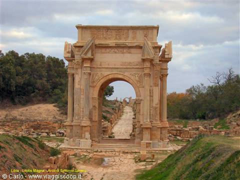 Stone Arch of Septimius Severus over paved road among ruins, Leptis Magna