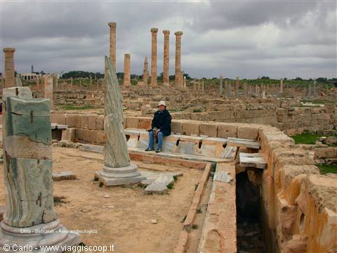 Tourist sitting among green marble columns in the Roman ruins of Sabratha