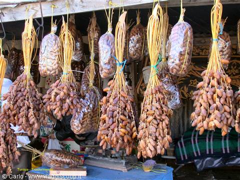 Bunches of dates hanging at a market stall under a wooden roof