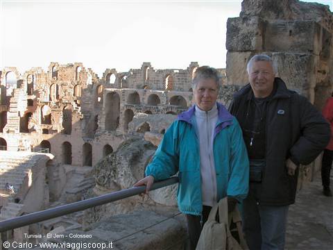Couple of tourists at El Jem Colosseum, Roman stone ruins under sunny light