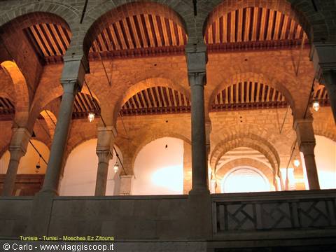 Stone arches and columns inside the Ez Zitouna Mosque, warm lighting