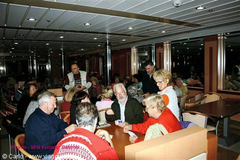Passengers playing cards in the lit lounge of the MN European Odyssey ferry