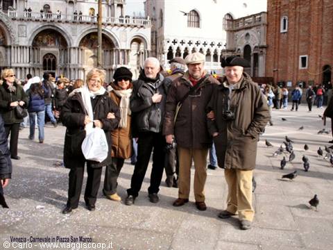 Group of tourists in coats posing in St Mark's Square, Venice, pigeons around