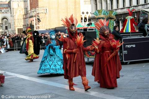 Red and blue masked carnival costumes parading in St. Mark's Square, Venice